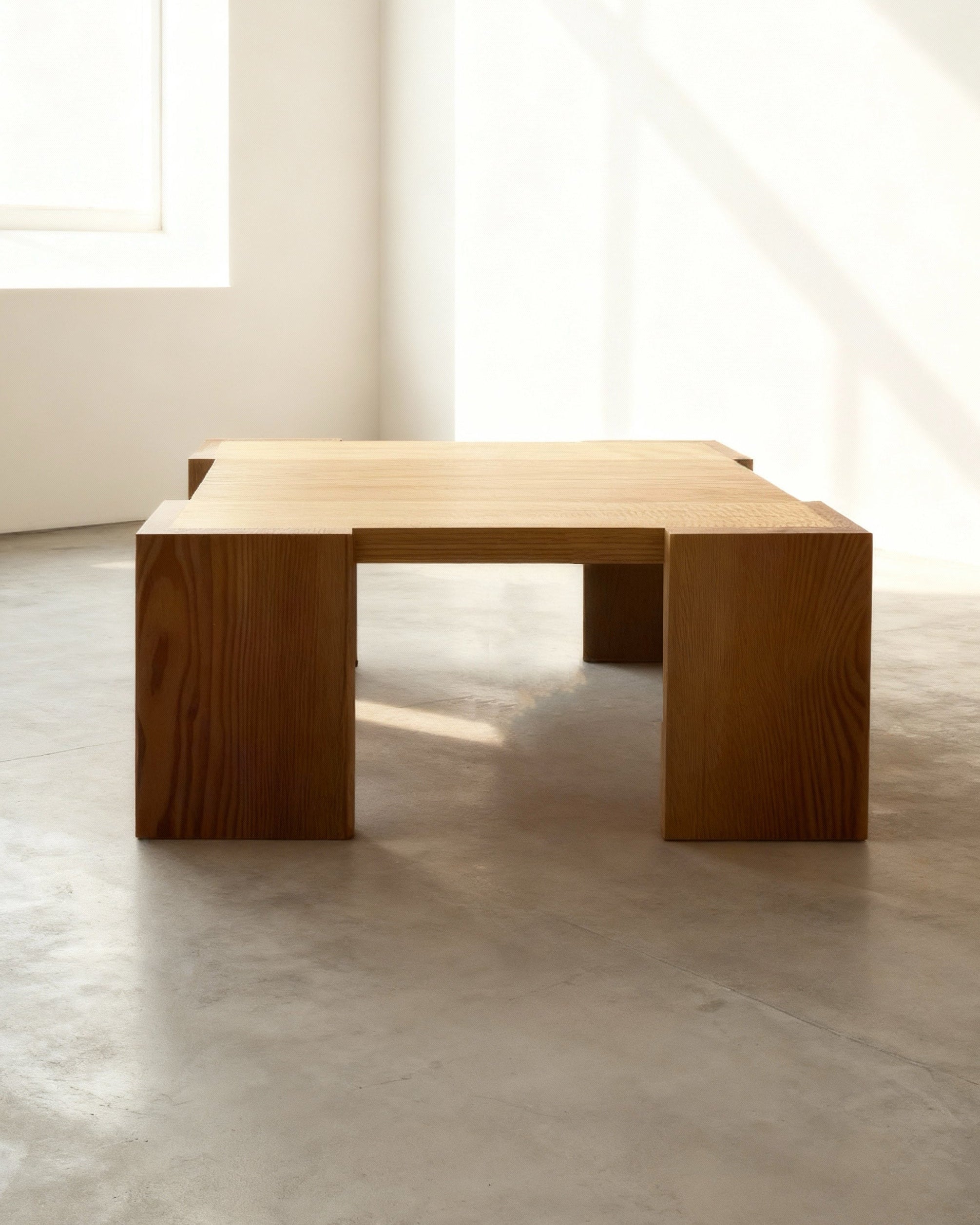 Wooden coffee table in a minimalistic room with large windows.