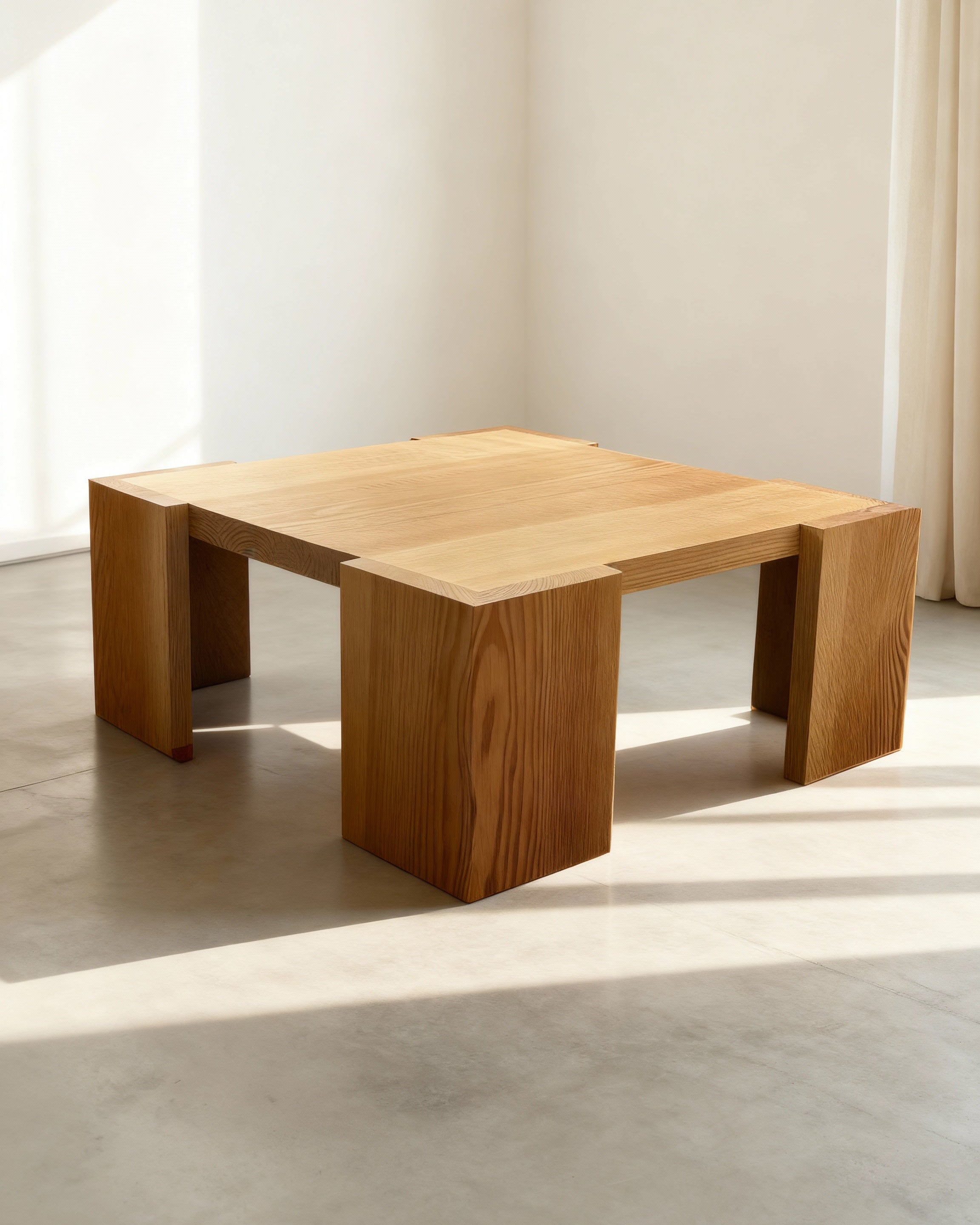 Wooden coffee table in a minimalistic room with sunlight streaming through a window.