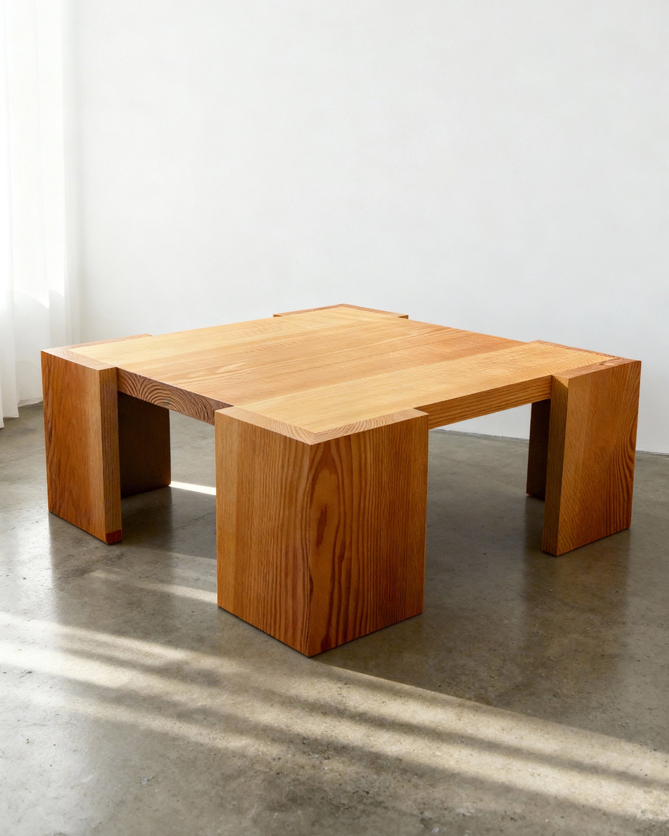 Wooden coffee table on a concrete floor with a white wall background