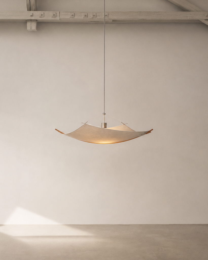 A modern pendant light with a wide, shallow bowl-shaped shade made of natural wood and a thin metal suspension rod, hanging in a minimalist room with a plaster wall and concrete floor.